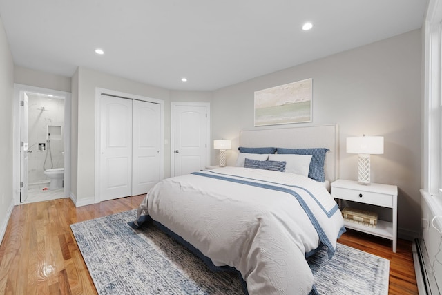 bedroom featuring light hardwood / wood-style floors, connected bathroom, and a baseboard heating unit