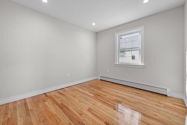 unfurnished room with a baseboard heating unit and light hardwood / wood-style flooring