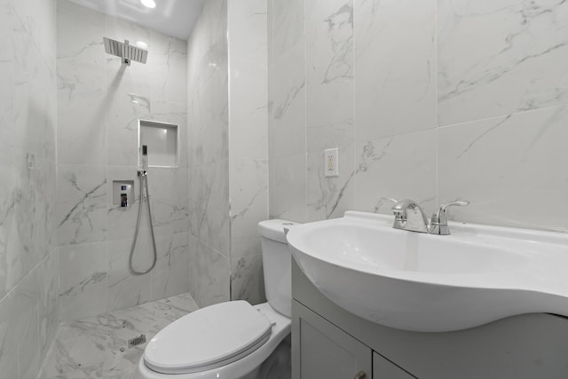 bathroom with toilet, vanity, and tiled shower