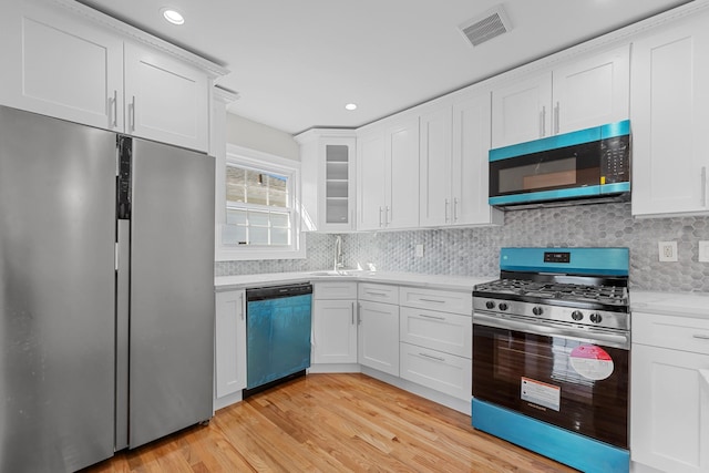 kitchen with white cabinets, stainless steel appliances, and light hardwood / wood-style flooring