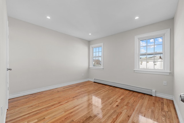 empty room featuring a baseboard heating unit and light wood-type flooring