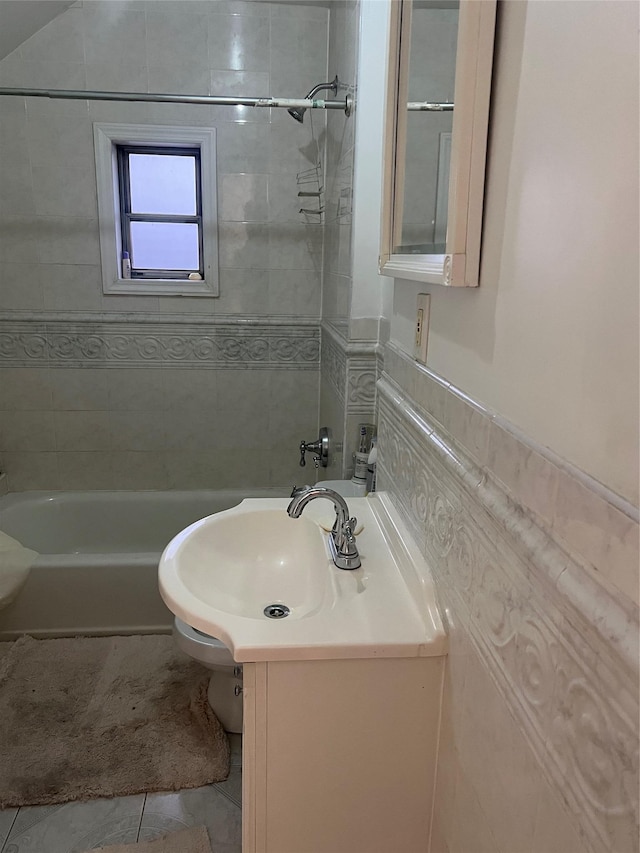 bathroom featuring tiled shower / bath combo, sink, and tile walls