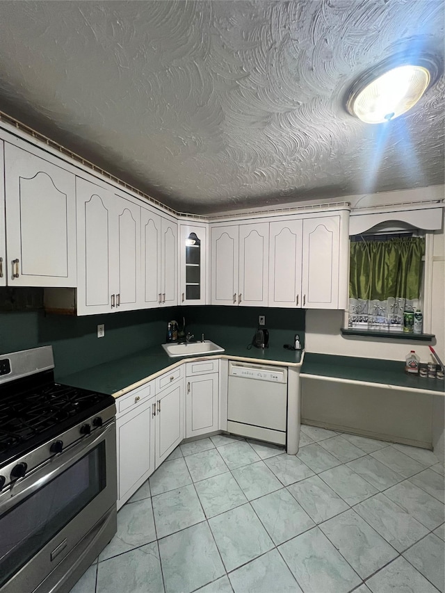 kitchen featuring sink, stainless steel range with gas stovetop, white dishwasher, a textured ceiling, and white cabinets