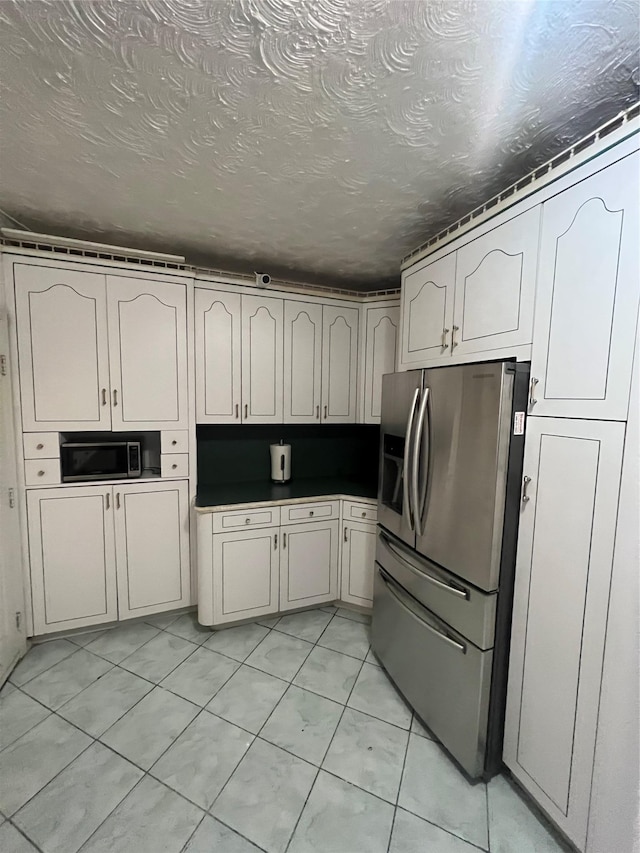 kitchen featuring stainless steel appliances, light tile patterned floors, and a textured ceiling