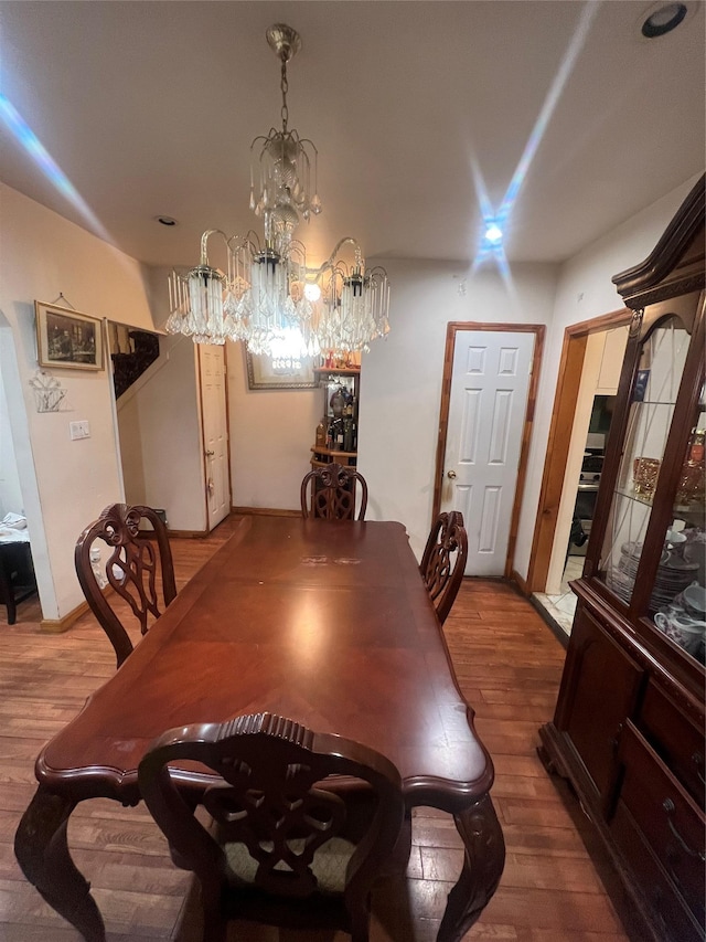 dining space featuring wood-type flooring and a notable chandelier