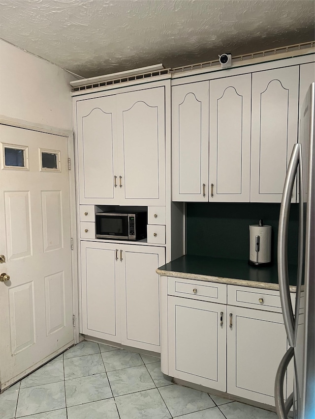 kitchen with stainless steel appliances, a textured ceiling, and white cabinets