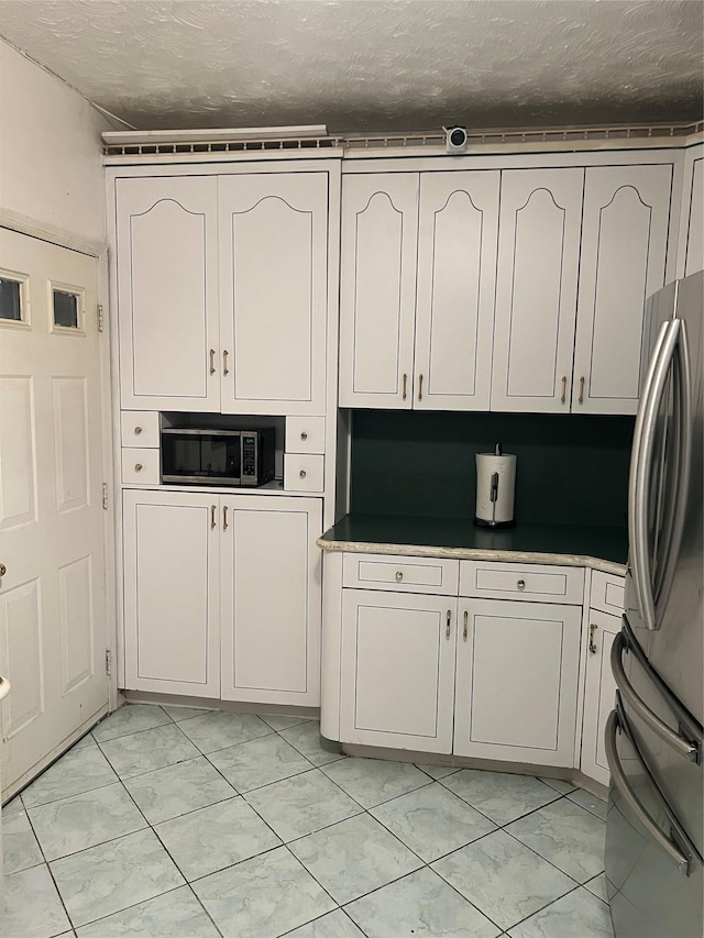 kitchen featuring a textured ceiling, white cabinets, and stainless steel refrigerator