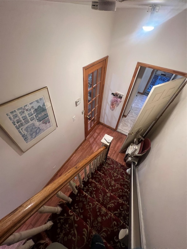 stairway featuring a towering ceiling and wood-type flooring