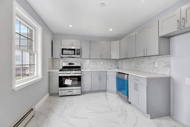 kitchen with a baseboard radiator, appliances with stainless steel finishes, gray cabinets, and sink