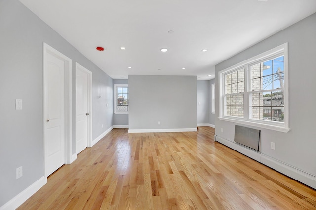 empty room with baseboard heating and light wood-type flooring