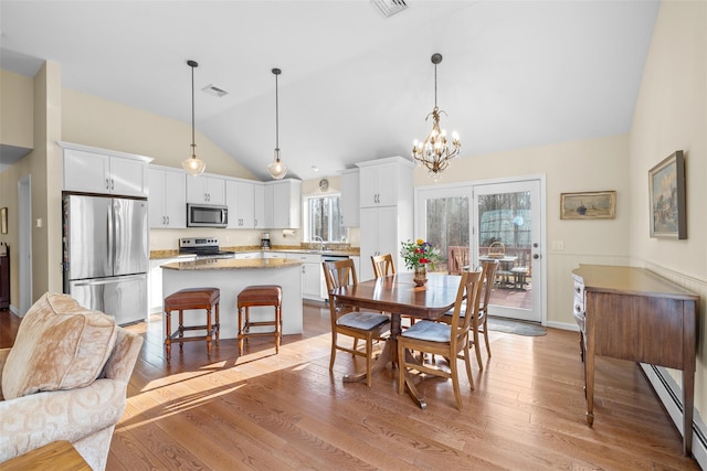 dining area featuring sink, lofted ceiling, a chandelier, and light wood-type flooring