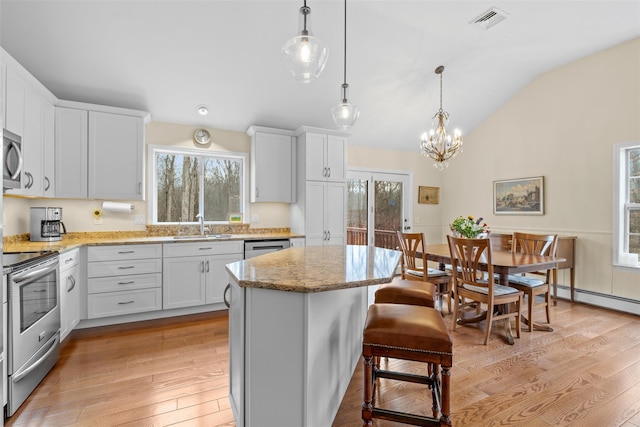 kitchen with hanging light fixtures, white cabinets, stainless steel appliances, and a center island