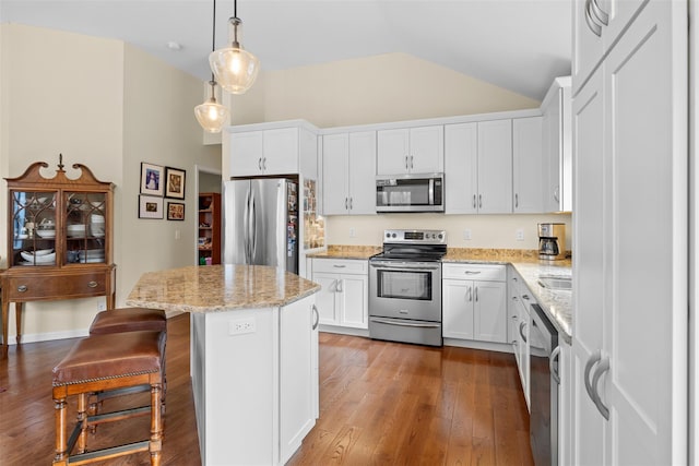 kitchen featuring lofted ceiling, a kitchen island, white cabinetry, hanging light fixtures, and appliances with stainless steel finishes