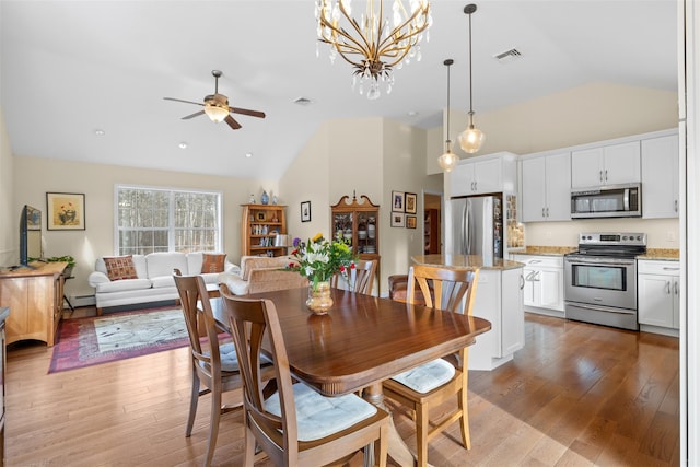 dining room with ceiling fan with notable chandelier, lofted ceiling, light hardwood / wood-style floors, and a baseboard radiator