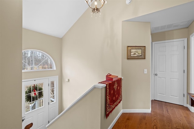 corridor with a notable chandelier and hardwood / wood-style floors