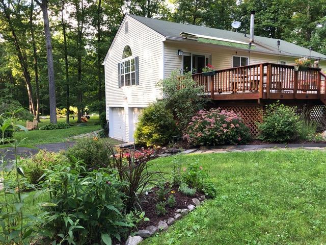 back of house with a lawn, a wooden deck, and a garage