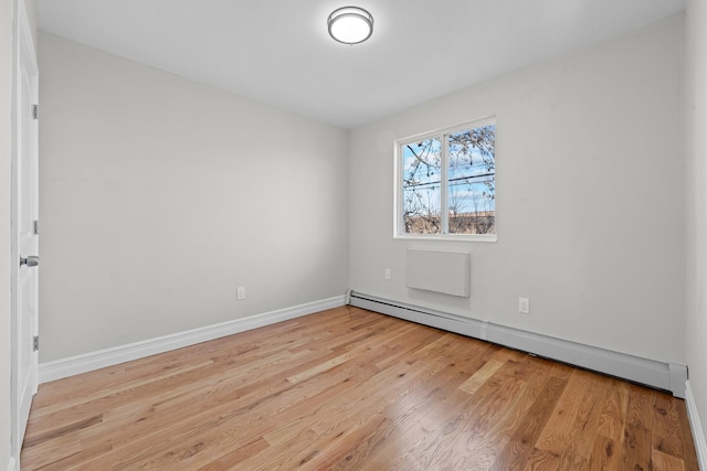 empty room featuring a baseboard radiator and light hardwood / wood-style flooring