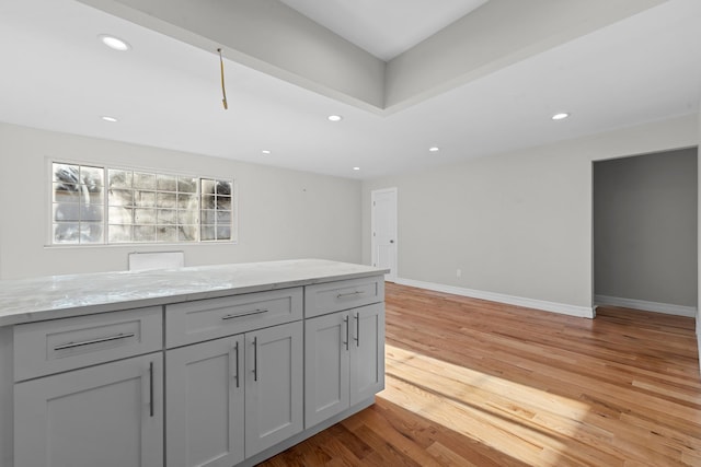 kitchen with light wood-type flooring, light stone countertops, and gray cabinetry