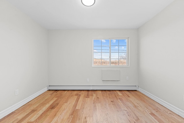 unfurnished room with baseboard heating and light hardwood / wood-style flooring