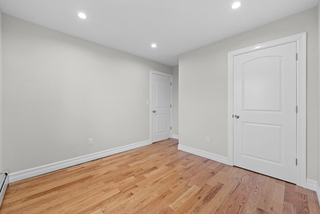 unfurnished room featuring a baseboard radiator and light wood-type flooring