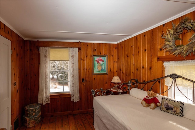 bedroom featuring wood walls, ornamental molding, and wood-type flooring