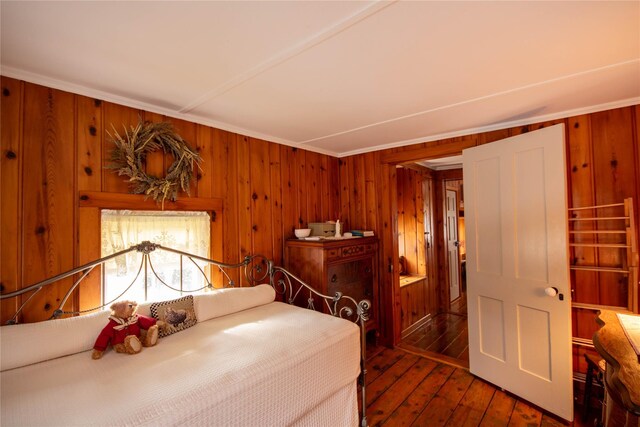 bedroom with dark hardwood / wood-style flooring and wooden walls