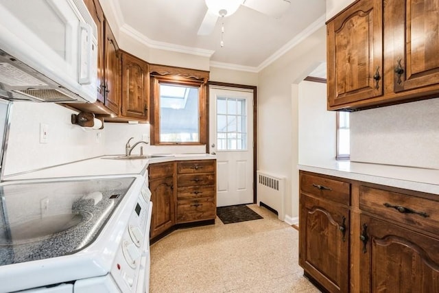 kitchen with radiator heating unit, ceiling fan, white appliances, crown molding, and sink