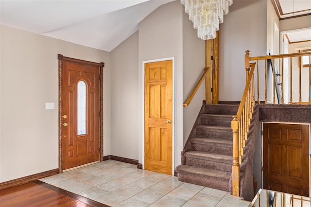 foyer with light hardwood / wood-style floors, vaulted ceiling, and an inviting chandelier