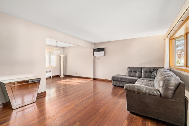 living room with hardwood / wood-style floors, radiator heating unit, a notable chandelier, and a healthy amount of sunlight