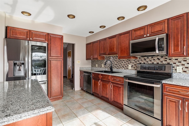 kitchen featuring light stone countertops, appliances with stainless steel finishes, decorative backsplash, and sink