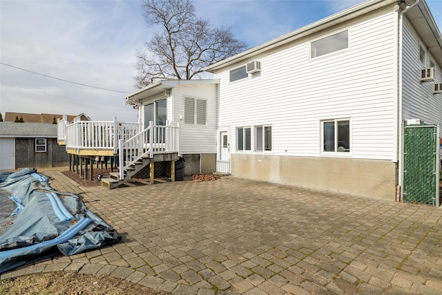 back of property with a deck, an AC wall unit, and a patio area