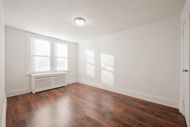 empty room featuring radiator and dark hardwood / wood-style flooring