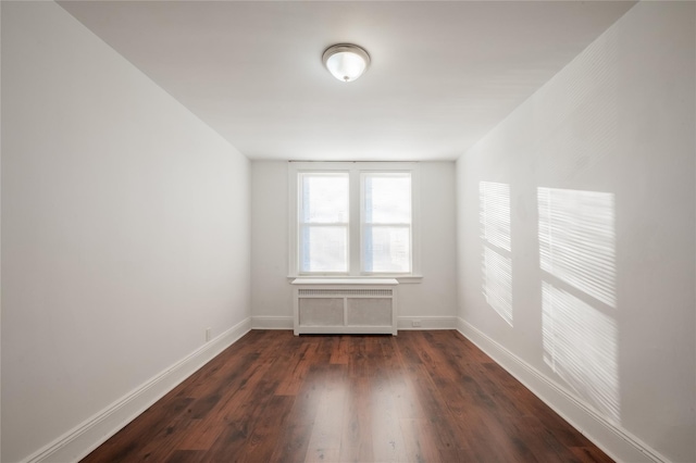 unfurnished room featuring radiator heating unit and dark hardwood / wood-style floors