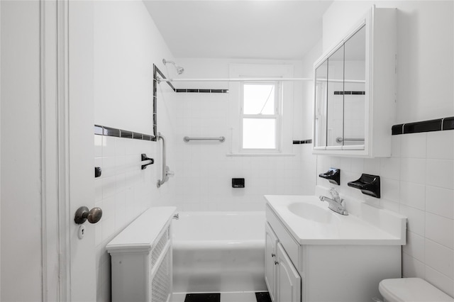 full bathroom featuring tiled shower / bath, vanity, tasteful backsplash, tile walls, and toilet