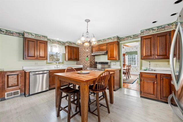 kitchen featuring an inviting chandelier, light hardwood / wood-style floors, appliances with stainless steel finishes, hanging light fixtures, and sink