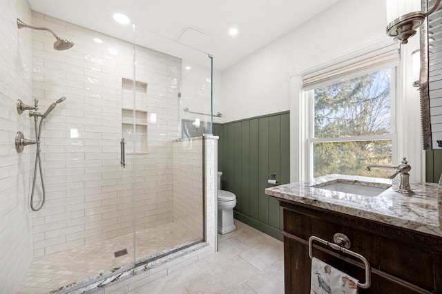 bathroom featuring toilet, tile patterned flooring, a shower with door, and vanity