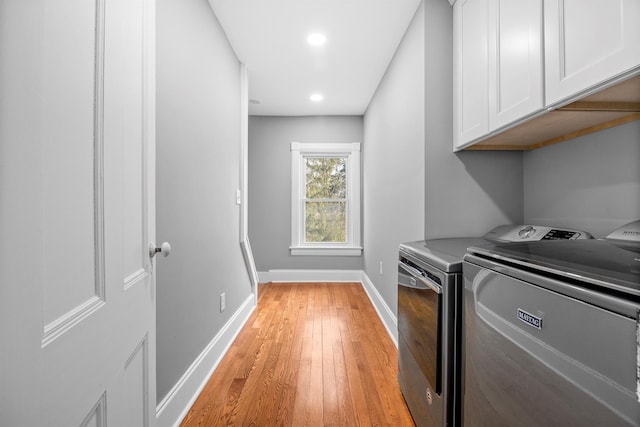 washroom featuring light wood-type flooring, washing machine and dryer, and cabinets