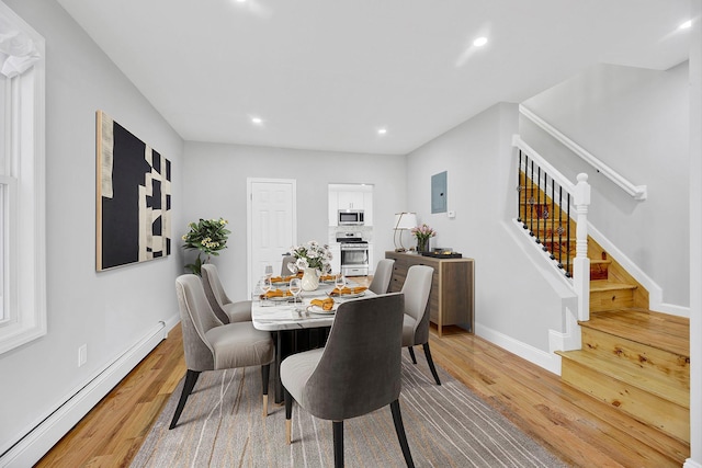 dining area with electric panel, hardwood / wood-style flooring, and a baseboard radiator