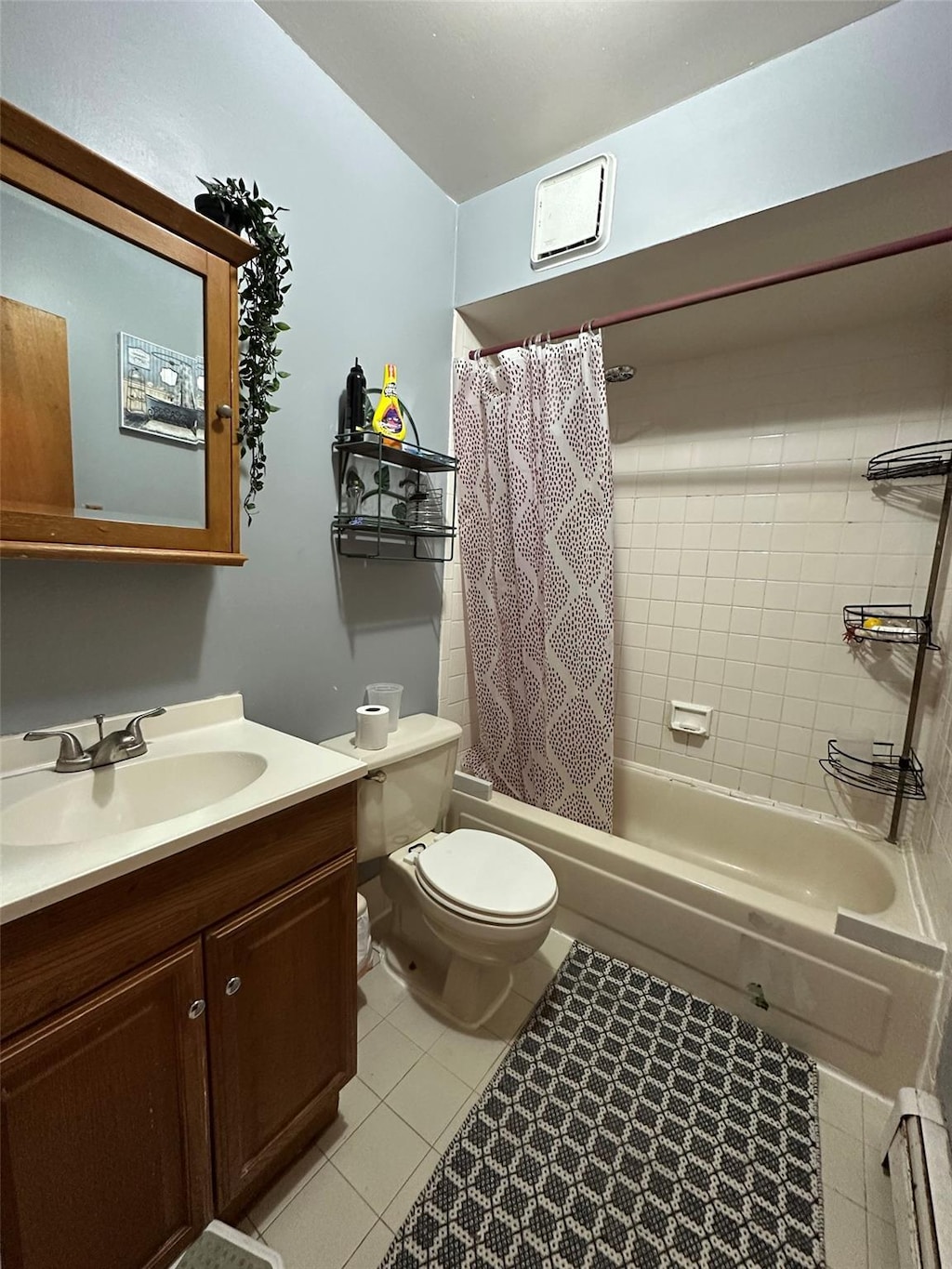 full bathroom featuring toilet, vanity, tile patterned floors, and shower / bathtub combination with curtain