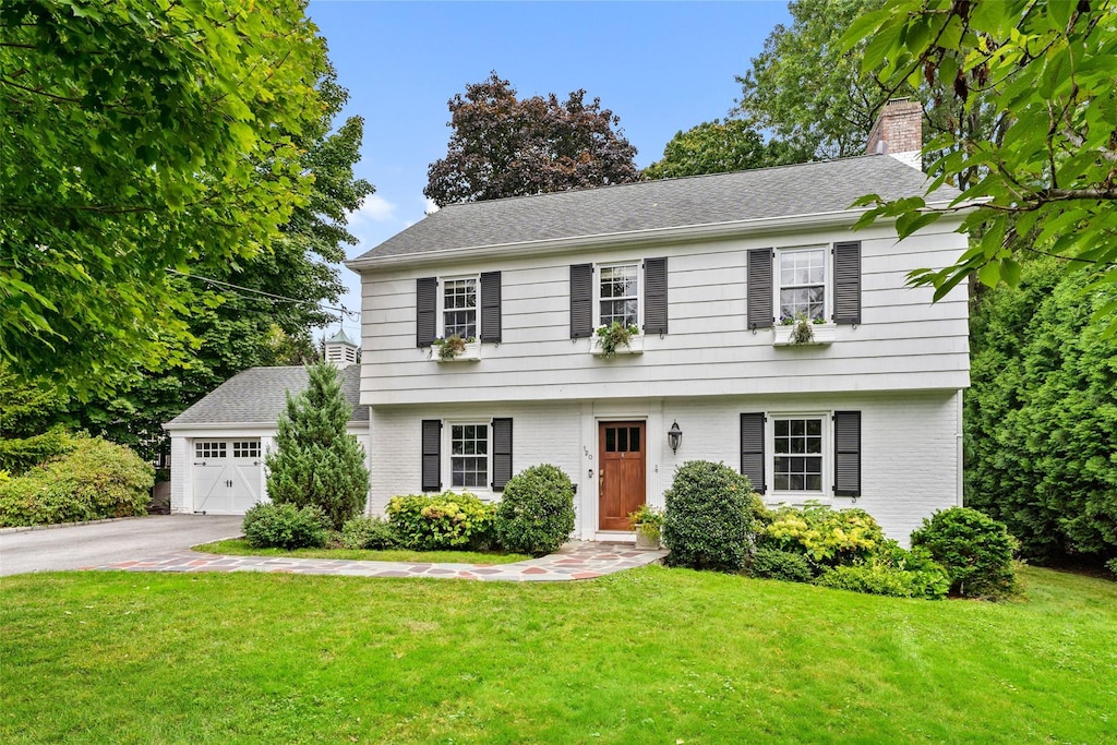 colonial inspired home featuring a garage and a front lawn