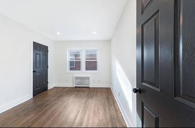 unfurnished room featuring heating unit and dark hardwood / wood-style flooring