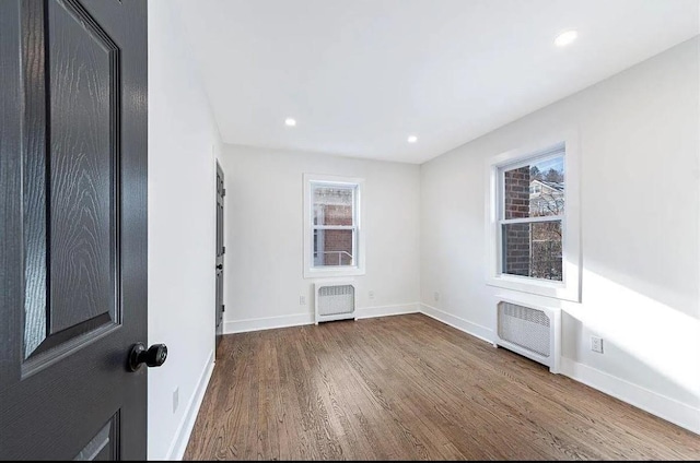 empty room featuring hardwood / wood-style floors and radiator heating unit