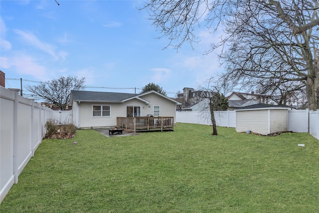 back of house featuring a deck, a storage unit, and a lawn