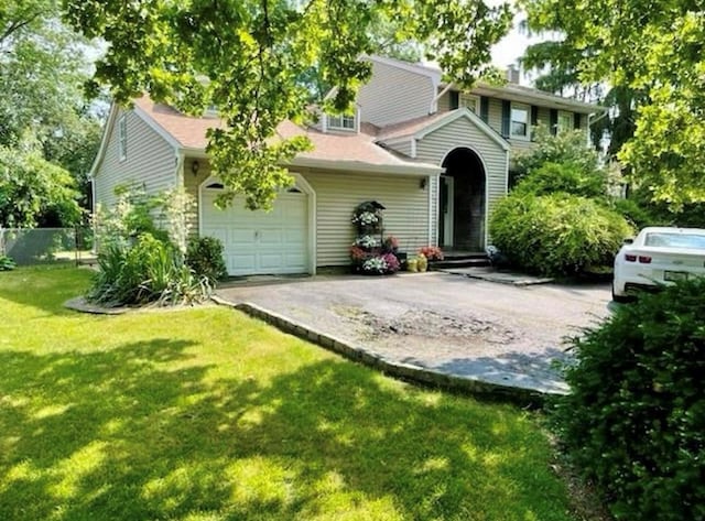 view of front facade featuring an attached garage, fence, aphalt driveway, and a front yard