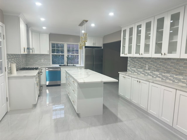 kitchen with decorative light fixtures, a center island, stainless steel appliances, white cabinets, and light stone counters