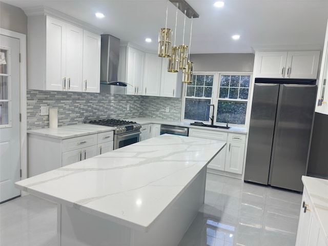 kitchen featuring wall chimney range hood, pendant lighting, decorative backsplash, white cabinetry, and appliances with stainless steel finishes