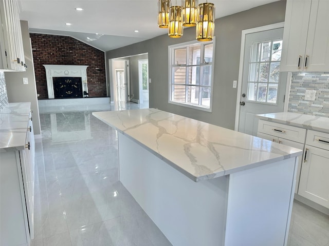 kitchen with lofted ceiling, a kitchen island, open floor plan, white cabinetry, and pendant lighting