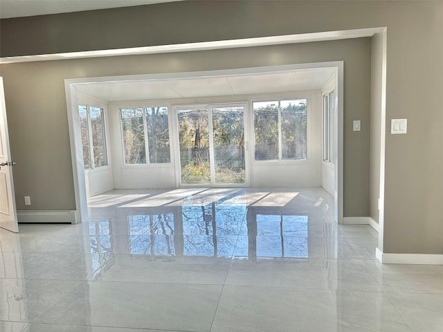 spare room featuring marble finish floor, baseboards, and a baseboard heating unit