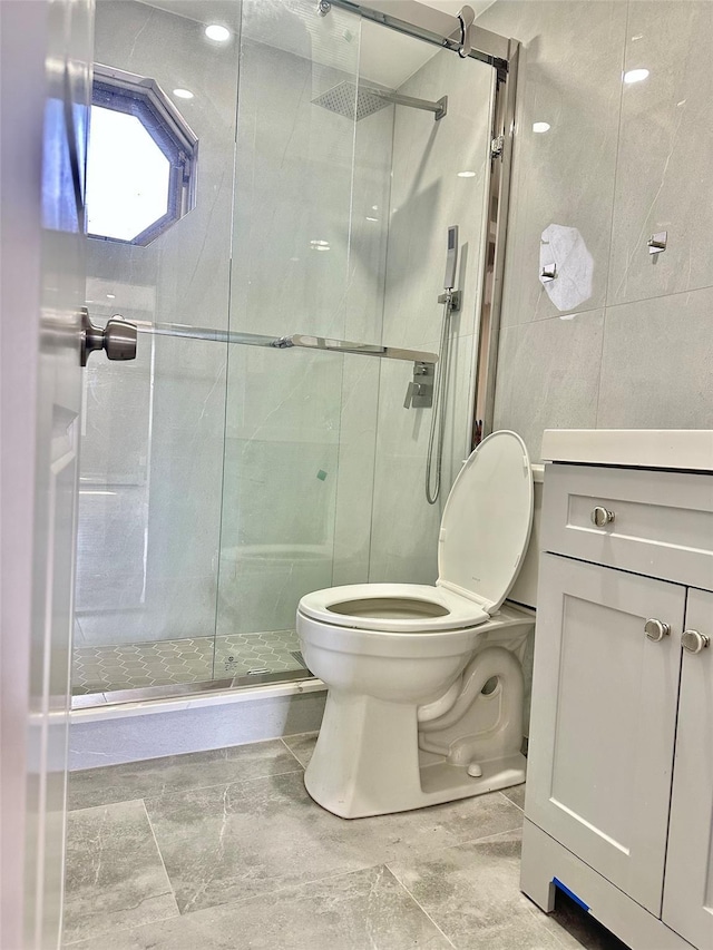 full bath with a stall shower, tile walls, toilet, and vanity