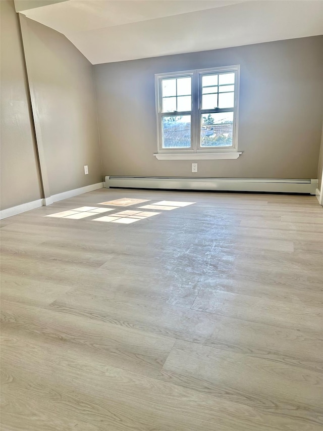 spare room with light wood-style floors, a baseboard radiator, and baseboards